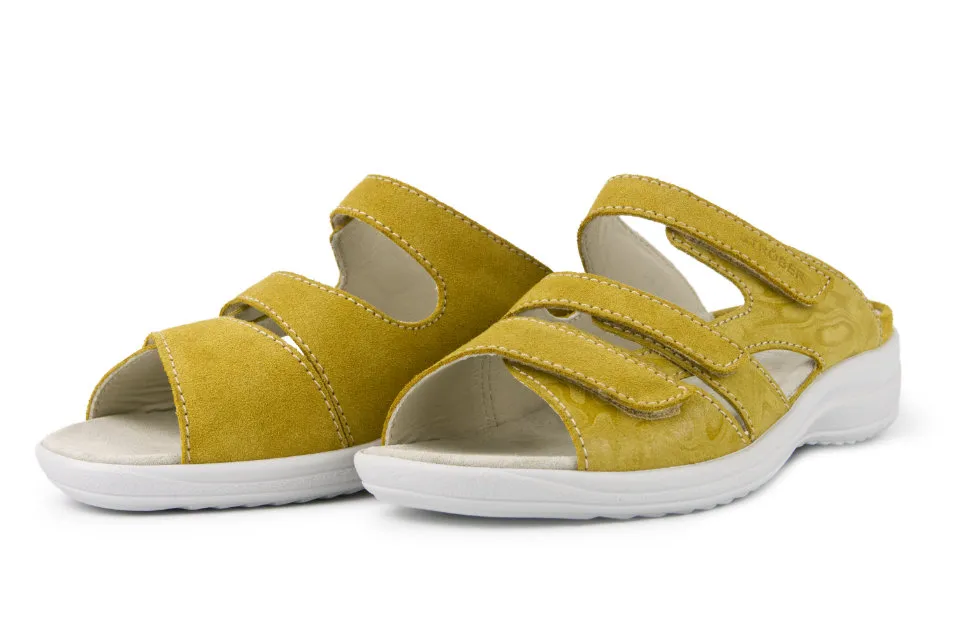 Helle gelbe HELLA Velour Schuhe stehen auf einem neutralen Untergrund, umgeben von natürlichem Licht, welches ihre Struktur hervorhebt.